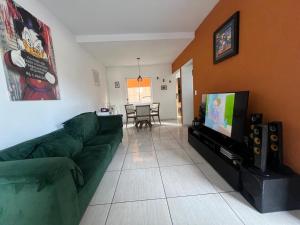 a living room with a green couch and a flat screen tv at Residencial Passos in Guaratuba