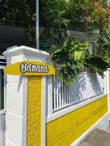 a yellow and white fence with a sign on it at Banana Homestay in Banyuwangi