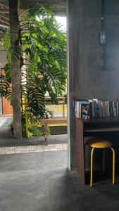 a desk with a yellow stool and a table with books at Banana Homestay in Banyuwangi