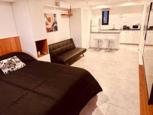 a bedroom with a bed and a couch and a kitchen at Center Suites Ideal parejas in La Plata