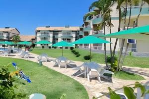 a lawn with chairs and umbrellas in front of a building at Aconchegante Flat B308 - Refúgio no Aldeia das Águas in Barra do Piraí