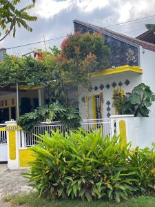 a white house with yellow accents and plants at Banana Homestay in Banyuwangi