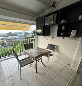 a kitchen with a table and chairs and a balcony at Duplex piscine vue imprenable Marina du Gosier avec citerne in Le Gosier