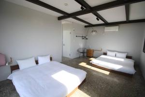 twee bedden in een kamer met witte lakens bij vebora eternity in Bora