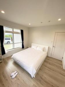 een slaapkamer met een wit bed en een paar pantoffels bij vebora shine in Bora