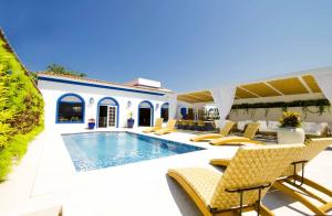 a villa with a swimming pool and chairs at Hotel Solar do Arco in Cabo Frio