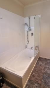 a bath tub with a shower in a bathroom at Home stay - Double Bed at Churton Park in Wellington +12 photos