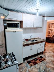 カンポス・ド・ジョルドンにあるCasa para temporadaのキッチン(白い冷蔵庫、コンロ付)