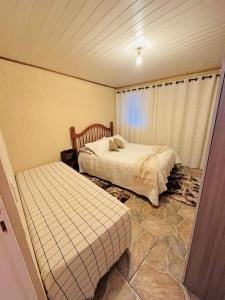 カンポス・ド・ジョルドンにあるCasa para temporadaのベッド2台と窓のある寝室