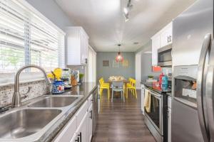 a kitchen with a sink and a table with yellow chairs at Gameroom, Bbq & Hot-tub By Lackland & Seaworld in San Antonio
