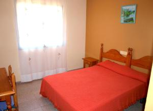 1 dormitorio con cama roja y ventana en APCOSTAS - Habitat Playa Romana, en Alcossebre