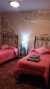 a bedroom with two beds with red covers and a rock wall at Casa Pilar in Canillas de Aceituno