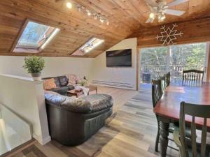 a living room with a couch and a table and a television at HappyCub- AC, Hot Tub, Fire Pit, Game Room! in Killington