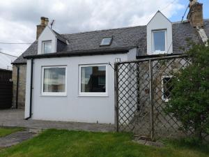 a white house with a fence in front of it at 3BR Cottage with Garden, Free Parking for 6 Guests in Alness +42 photos