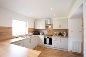 a kitchen with white cabinets and a sink and a window at 3BR Cottage with Garden, Free Parking for 6 Guests in Alness