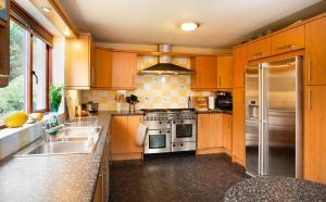 a kitchen with wooden cabinets and a stainless steel refrigerator at 5-Bed Highland Lodge - NC500 - Sleeps 10 in Alness