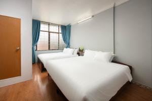 two large white beds in a room with a window at The La Renta Hotel & Spa in Hanoi