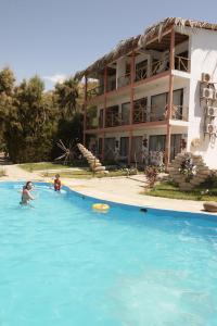 two people in a swimming pool next to a hotel at H0TELIER Home, Máncora in Máncora