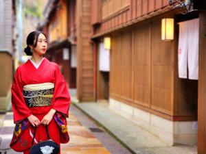 a woman in a red dress walking down a street at ひがし茶屋街らしく金沢 Hotel Rashiku kanazawa in Kanazawa