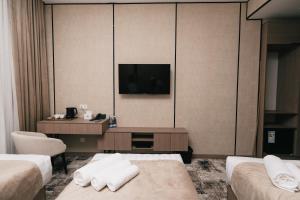 a hotel room with two beds and a television at Grand Castle Hotel in Urganch