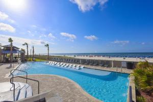 a swimming pool with lounge chairs and the beach at The Oasis at Orange Beach in Orange Beach