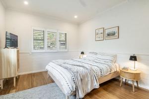 a white bedroom with a bed and two windows at Frangipani Cottage - Belle Escapes Byron Bay | Winter Escape Deal | Stay Longer & Save | 1 June – 31 August in Byron Bay
