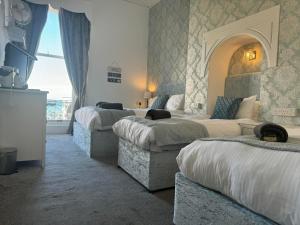 a hotel room with three beds and a couch at The Jubilee Hotel East - with NEWLY REFURBISHED SPA FACILITIES - GAMESPIT - AND SMOKEHOUSE in Weymouth +75 photos