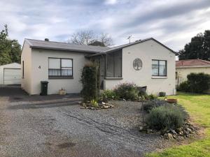 a white house with black windows and a driveway at Strangways Villa in Mount Gambier