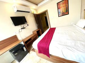 a bedroom with a bed and a flat screen tv at Hotel mauji's legacy in Allahābād
