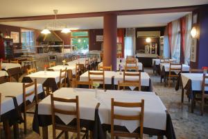 un comedor con mesas blancas y sillas de madera en Hotel La Planada en Ordino