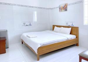 a bedroom with a bed in a white room at Nhà Khách Vạn Thành in Cà Mau