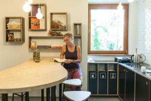 a woman standing in a kitchen reading a book at Youth Hostel Proteus Postojna in Postojna