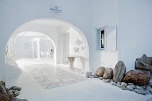 a white room with a stone floor and an archway at Mykonos Bay Resort & Villas in Mikonos