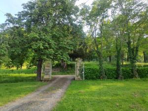 a gate in a field with a tree and a dirt road at Maison bastide Périgord in Castillonnès +1 photo