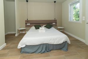 Un dormitorio con una gran cama blanca con dos mesas. en L Arberet 2 village, 4 étoiles, en Vendays-Montalivet