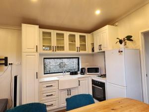 北帕默斯顿Cozy self contained Tiny Home的厨房配有白色橱柜和白色冰箱
