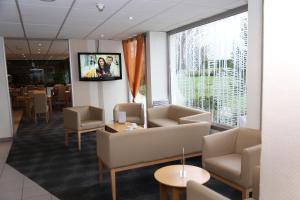 a waiting room with couches and a tv on a wall at ibis Styles Orléans in La Chapelle-Saint-Mesmin