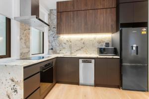 Una cocina con electrodomésticos de acero inoxidable y gabinetes de madera. en Victoria Street Apartments by Urban Rest, en Auckland