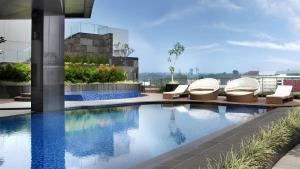 a swimming pool with lounge chairs on a building at PO Hotel Semarang in Semarang
