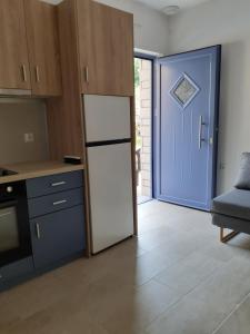 a kitchen with a refrigerator and a blue door at Αλκυονη Διαμερισματα in Paralia Vrachou