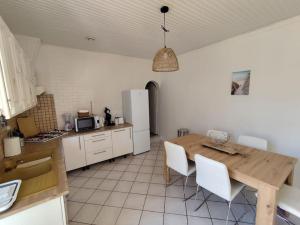 Una cocina con una mesa de madera y gabinetes blancos. en Maison 8 couchages Arcachon, en Arcachon