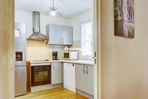 a kitchen with white cabinets and a white refrigerator at Ô Carré d'Or - T3 proche du centre ville- Saint-Denis in Saint-Denis