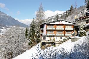 a building on a snow covered slope with a mountain at Herzblut Wohlfühl Appartements in Oetz