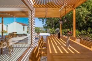 索利纳Villa 4 with Pool Soline, Krk, 280 m from beach, by 4Villas的甲板上配有木长椅和桌椅