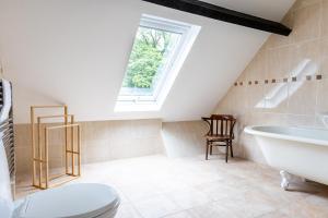 a bathroom with a toilet and a tub and a window at The Coach House in Lea +73 photos