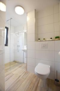 a white bathroom with a toilet and a sink at Domki na Wodnej in Kołobrzeg