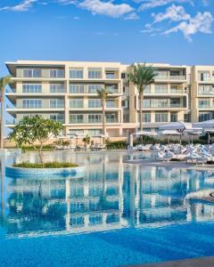 a hotel with a swimming pool in front of a building at Marassi, Luxury Suite in Address Beach resort! service apartment in El Alamein