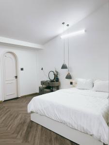 - une chambre blanche avec un grand lit blanc et une porte dans l'établissement Kinh Do Homestay, à Hương Trà