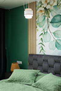 a bedroom with a bed and a green wall at Green Blooming Studio in Baia Mare