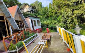 a yard with benches and a house in the background at Amar Bari Happy Valley Cottages by StayApart in Mangpu